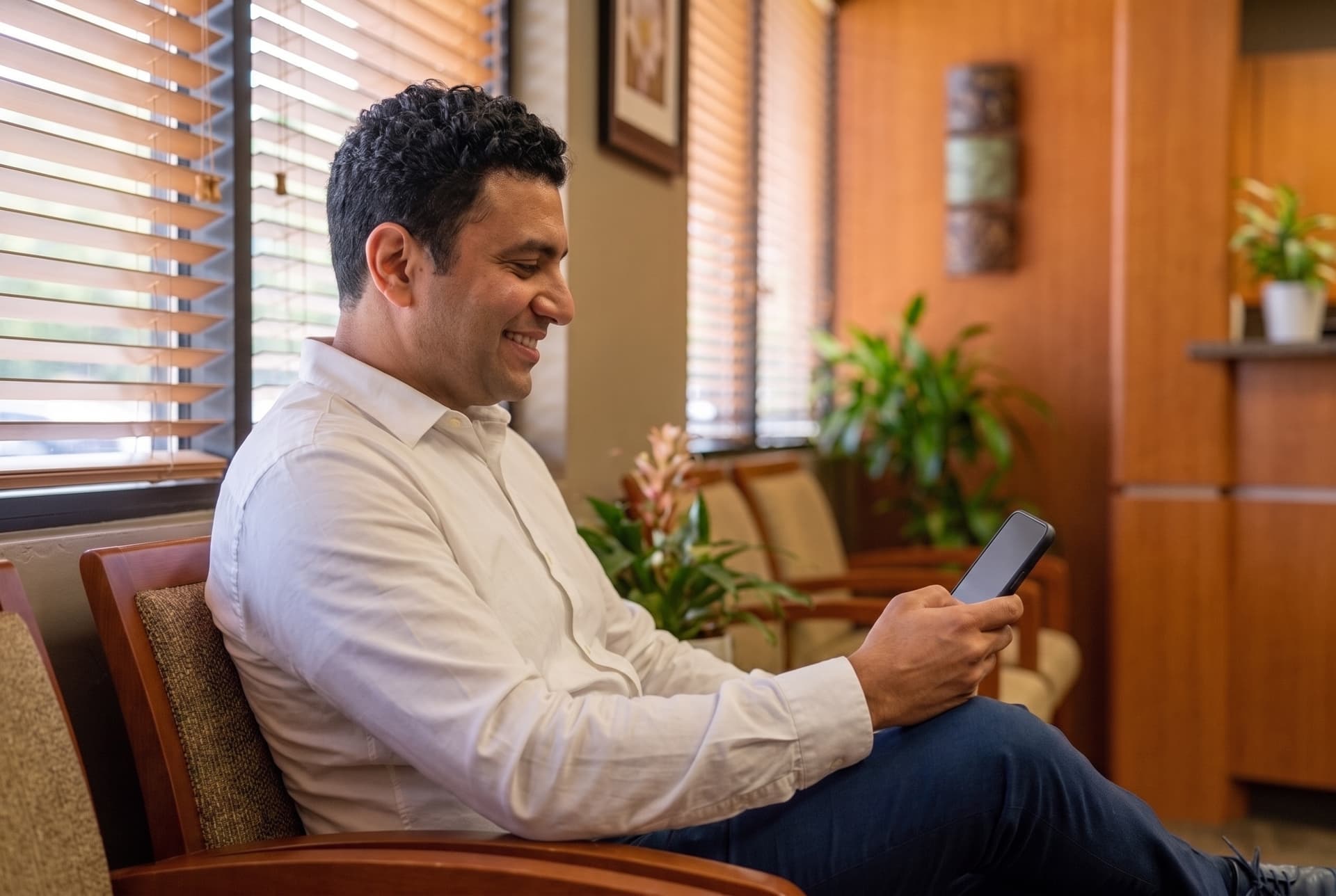 A patient seated in the waiting area checking his phone