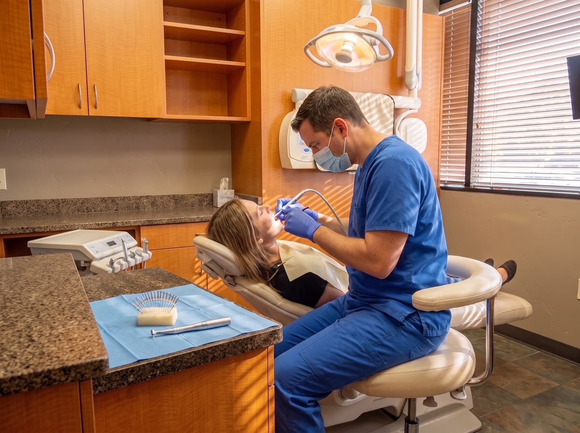 A clinician working with an endodontic handpiece on a reclined patient, root canal files on the field in the foreground